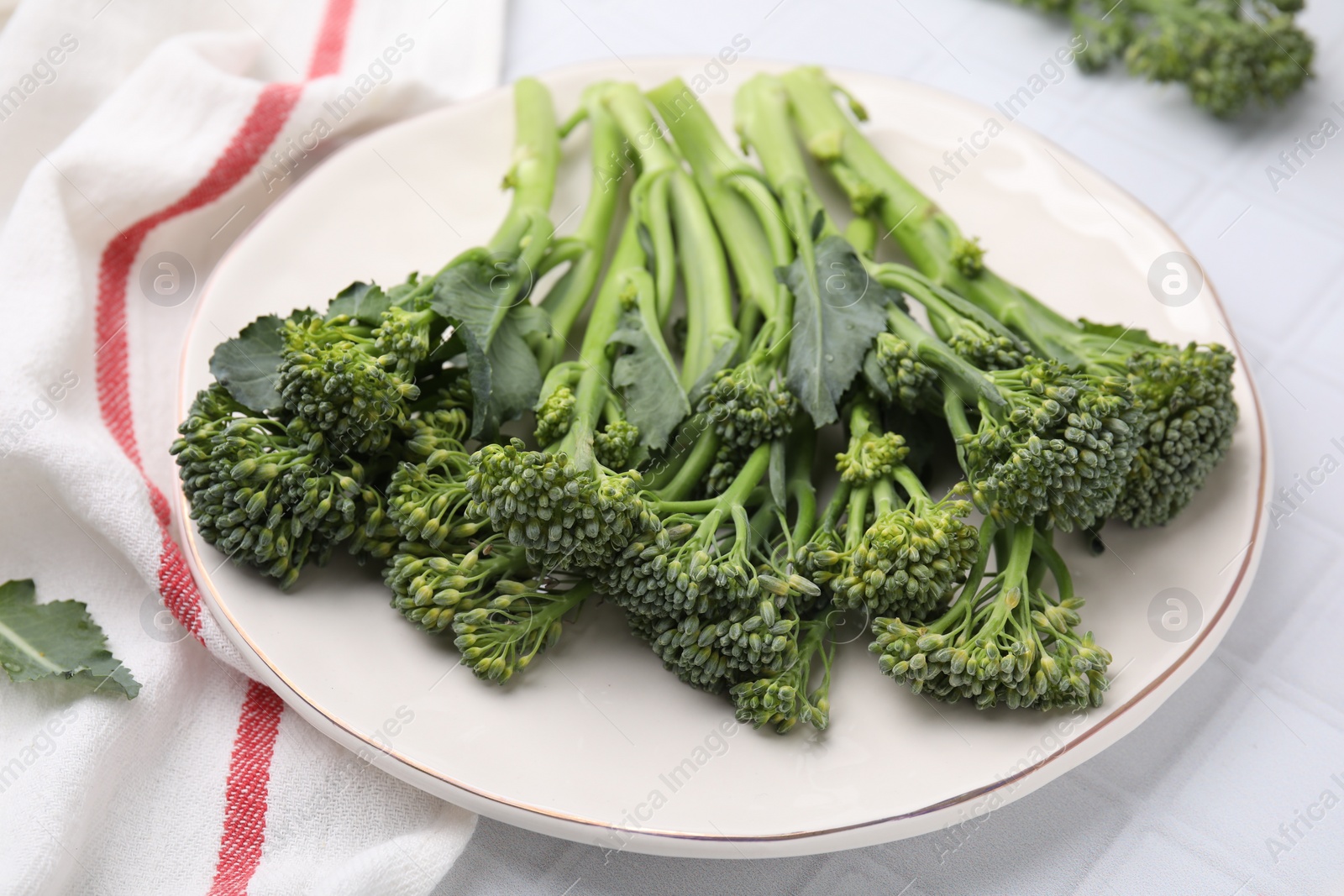 Photo of Fresh raw broccolini on white tiled table, closeup. Healthy food