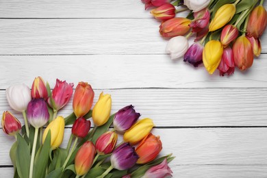 Photo of Beautiful colorful tulip flowers on white wooden table, flat lay. Space for text