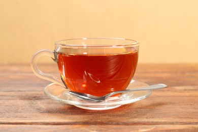 Glass cup of tea and spoon on wooden table