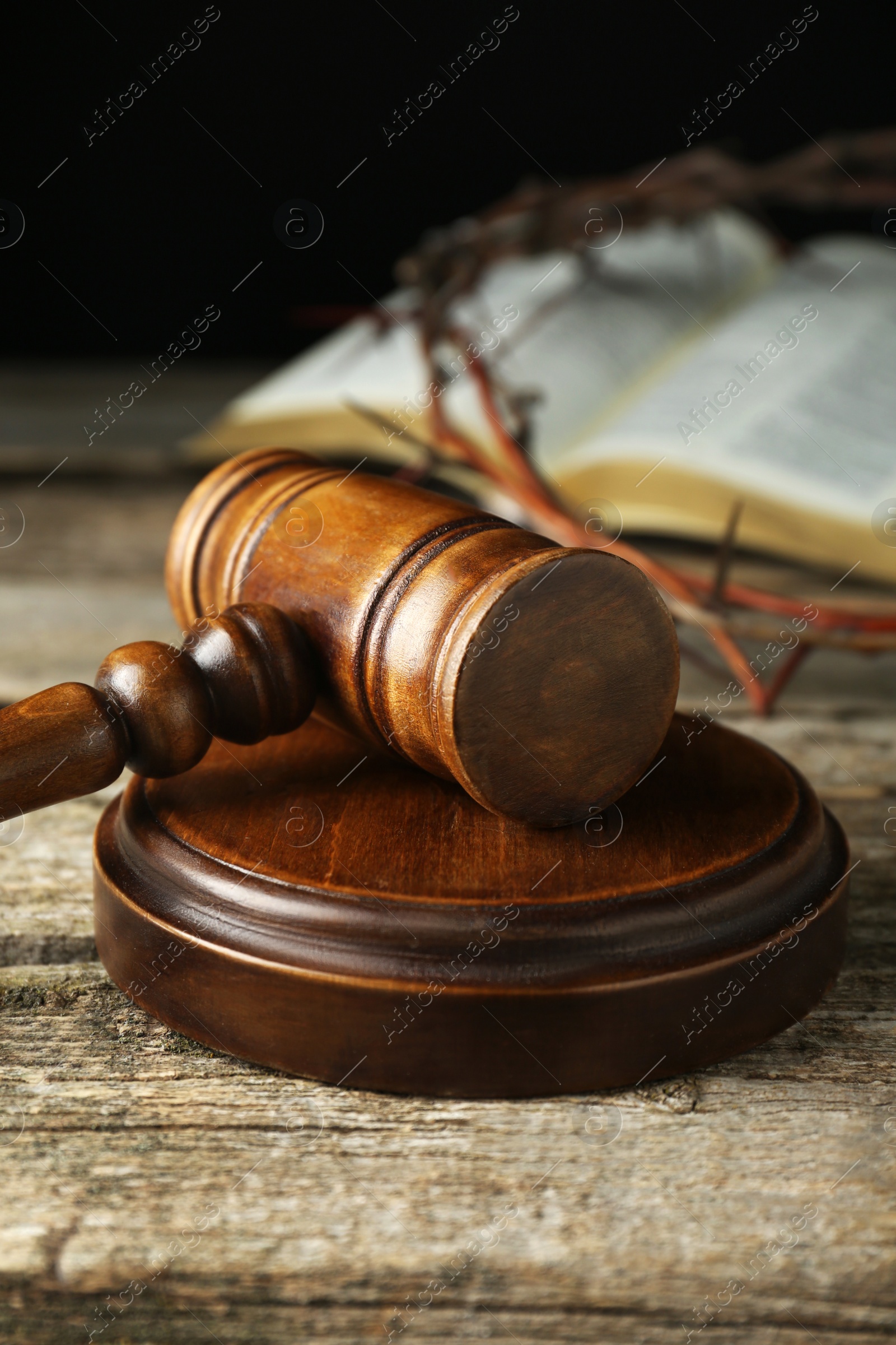 Photo of Judge gavel on old wooden table against black background, closeup