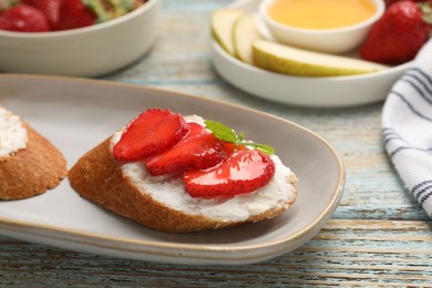 Delicious ricotta bruschettas with strawberry and mint on wooden table, closeup