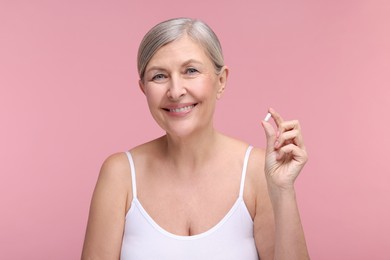 Photo of Beautiful woman with vitamin capsule on pink background