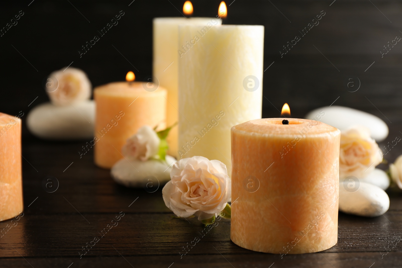 Photo of Burning candles, spa stones and flowers on table. Space for text