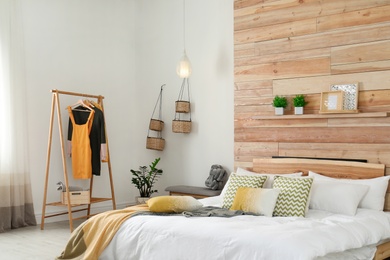 Photo of Stylish room interior with comfortable bed near wooden wall