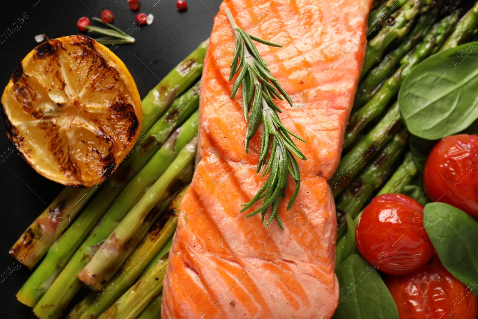 Photo of Tasty grilled salmon with tomatoes, asparagus and spices on plate, top view