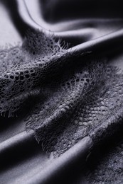 Photo of Beautiful lace with pattern on black fabric, closeup