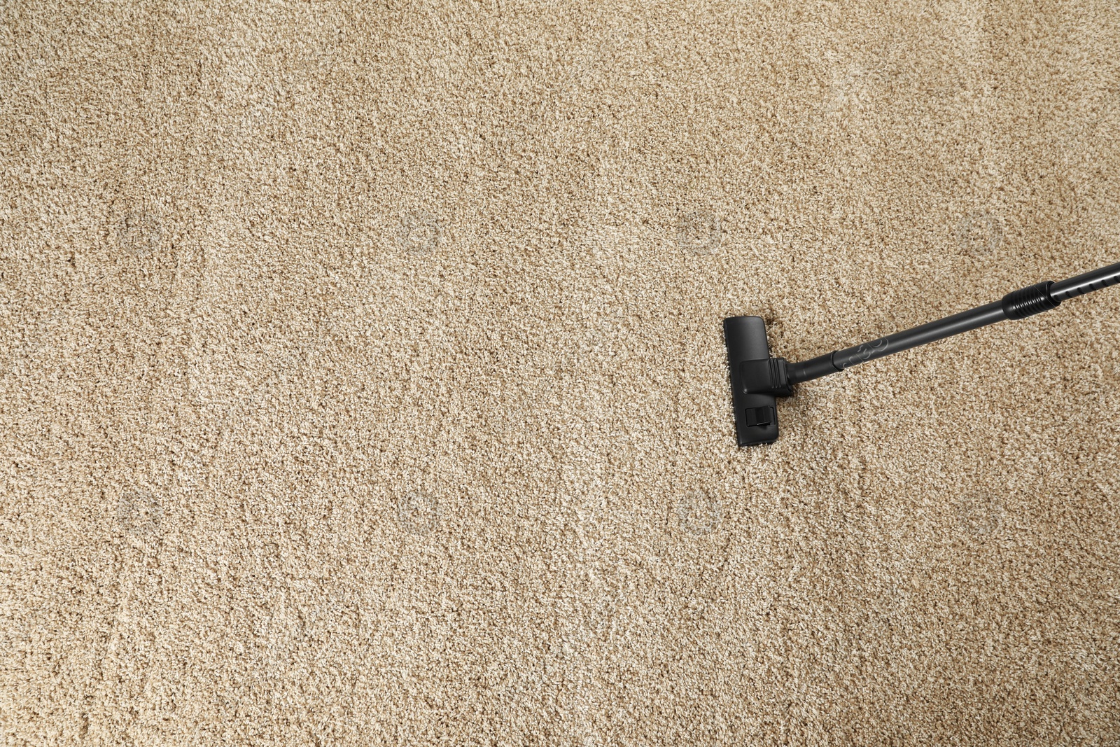 Photo of Removing dirt from beige carpet with modern vacuum cleaner, above view. Space for text