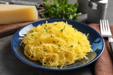 Plate with cooked spaghetti squash on table