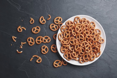 Delicious pretzel crackers on black table, flat lay