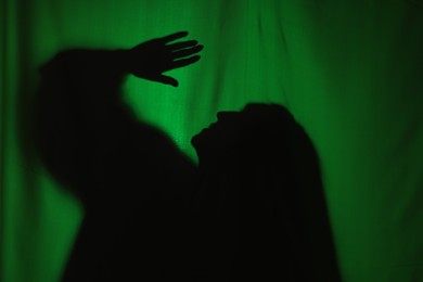 Photo of Silhouette of creepy ghost behind dark green cloth