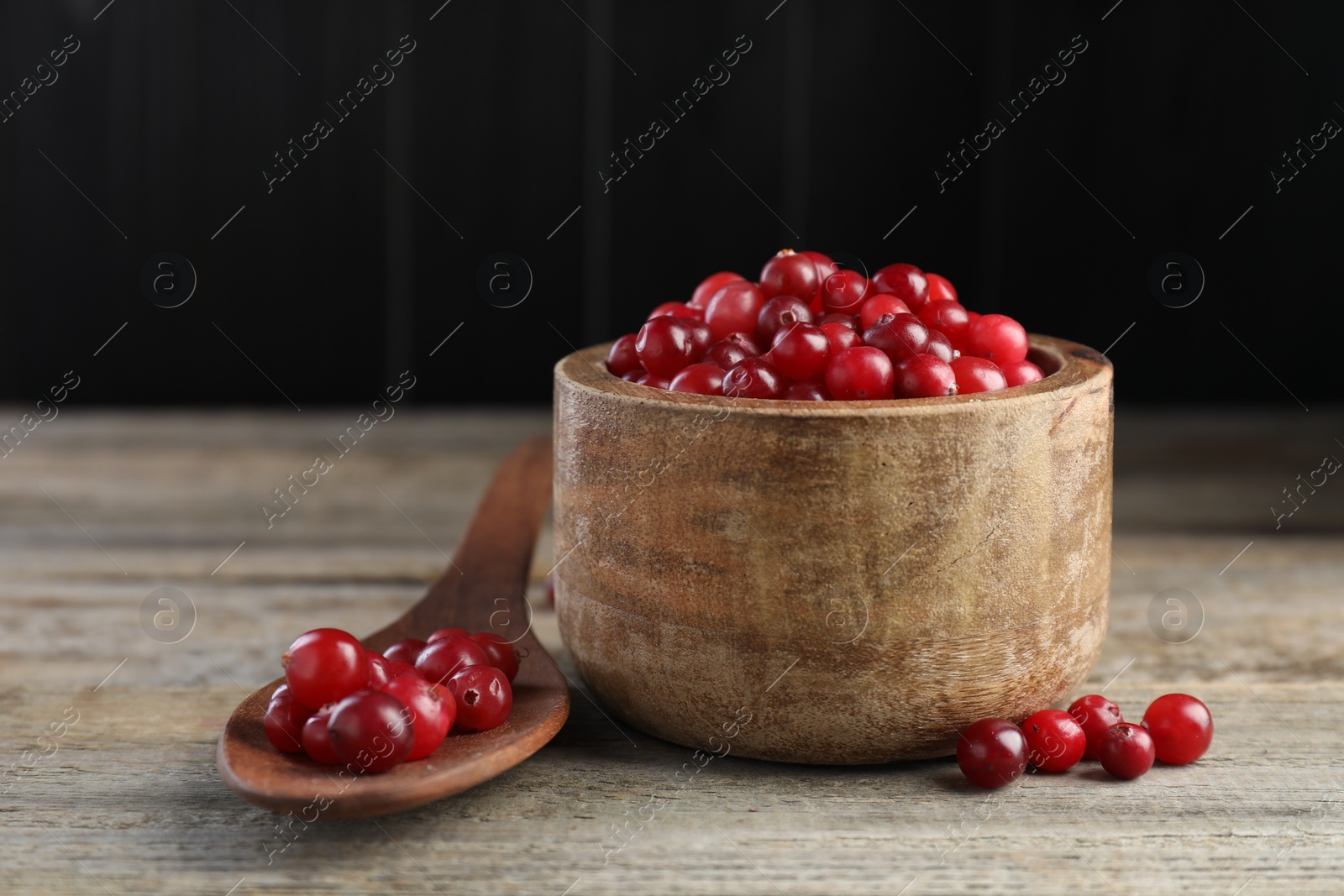 Photo of Cranberries in bowl and spoon on wooden table