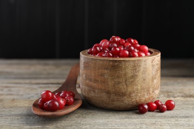 Photo of Cranberries in bowl and spoon on wooden table