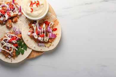 Photo of Delicious tacos with vegetables, meat and sauce on white marble table, top view. Space for text