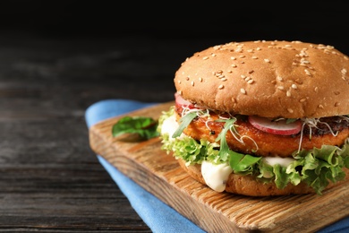 Board with tasty vegetarian burger on wooden table