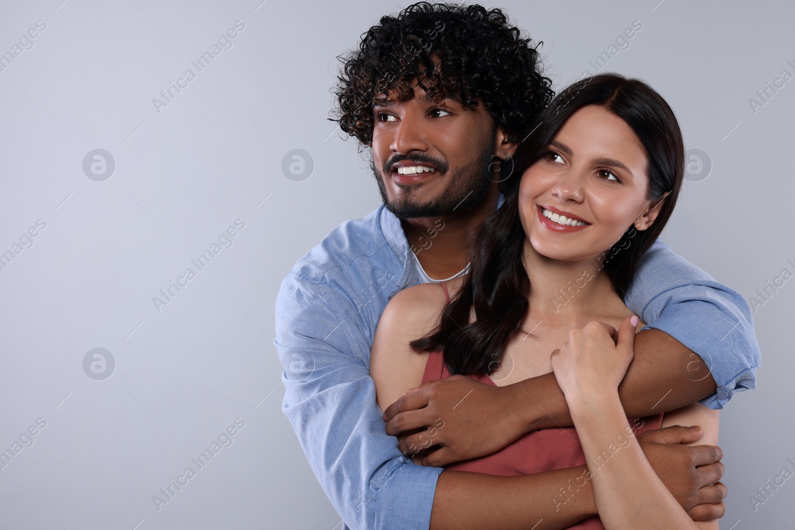 Photo of International dating. Happy couple hugging on light grey background, space for text