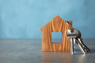 Bunch of keys and house model on table against color background. Space for text