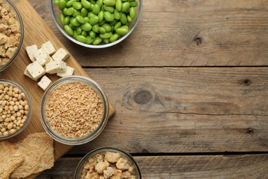 Different organic soy products on wooden table, flat lay. Space for text