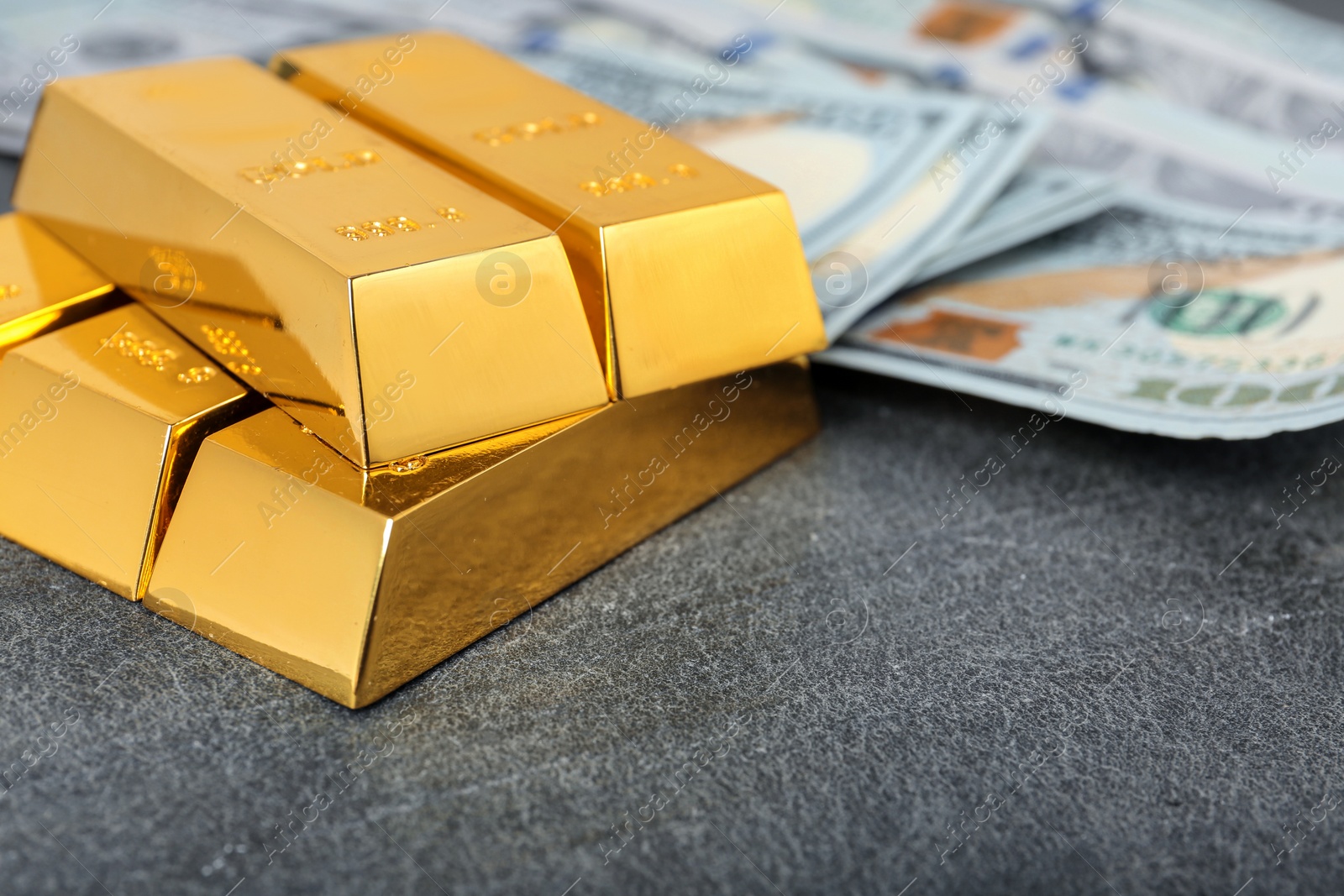 Photo of Stacked gold bars and dollar bills on table, closeup. Space for text