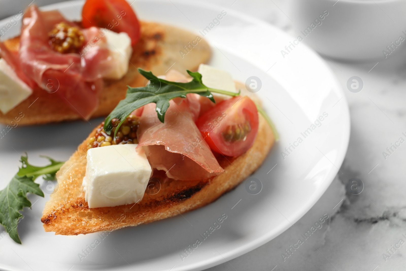 Photo of Plate of tasty bruschettas with prosciutto on table, closeup