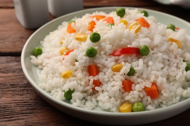 Photo of Delicious rice with vegetables on wooden table, closeup
