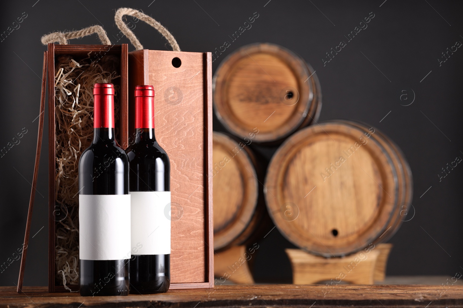 Photo of Wooden boxes and wine bottles on table against dark background. Space for text