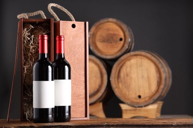 Photo of Wooden boxes and wine bottles on table against dark background. Space for text