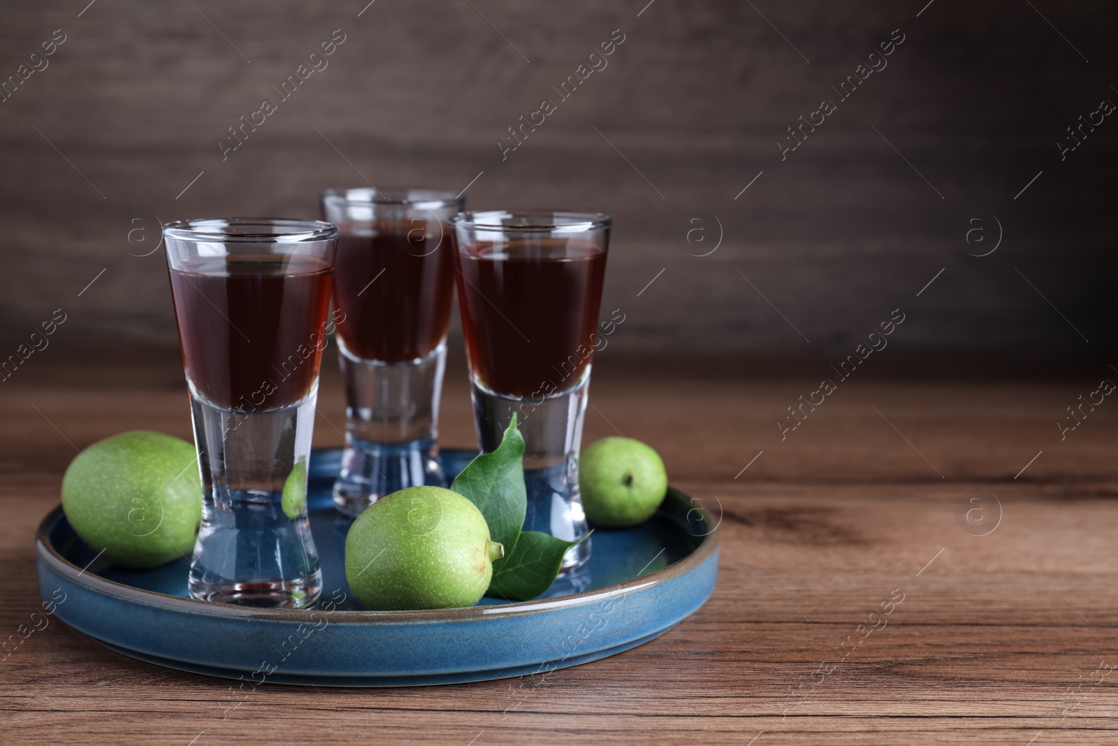 Photo of Delicious liqueur and green walnuts on wooden table. Space for text