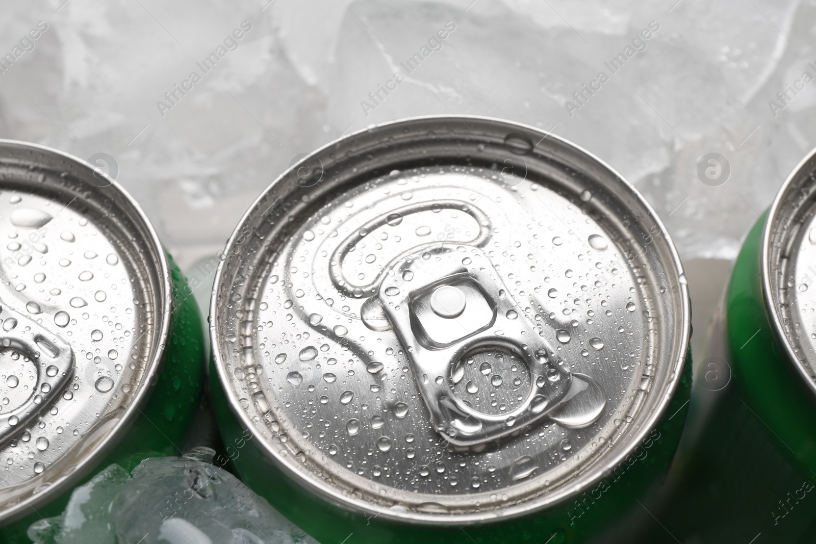 Photo of Energy drinks in wet cans and ice cubes, closeup