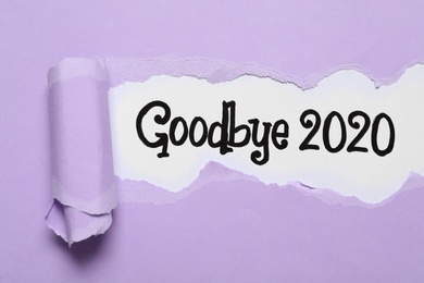 Text Goodbye 2020 on white background, top view through torn lilac paper