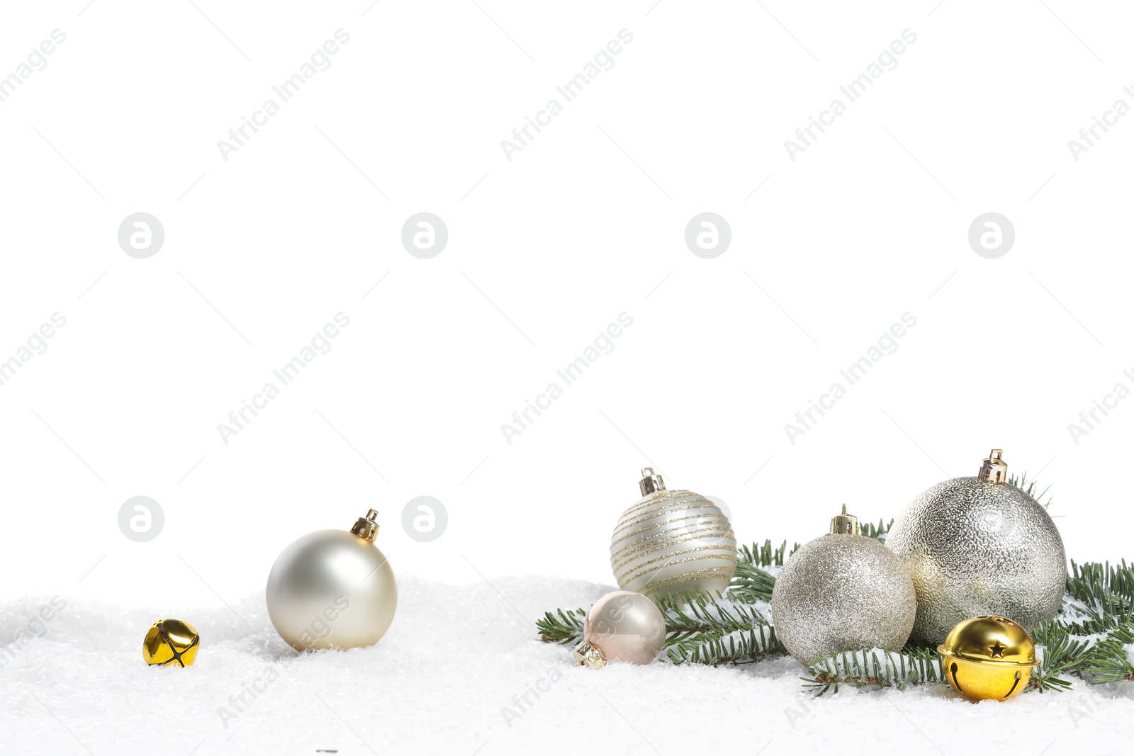 Photo of Beautiful Christmas balls, fir tree branch and sleigh bells on snow against white background