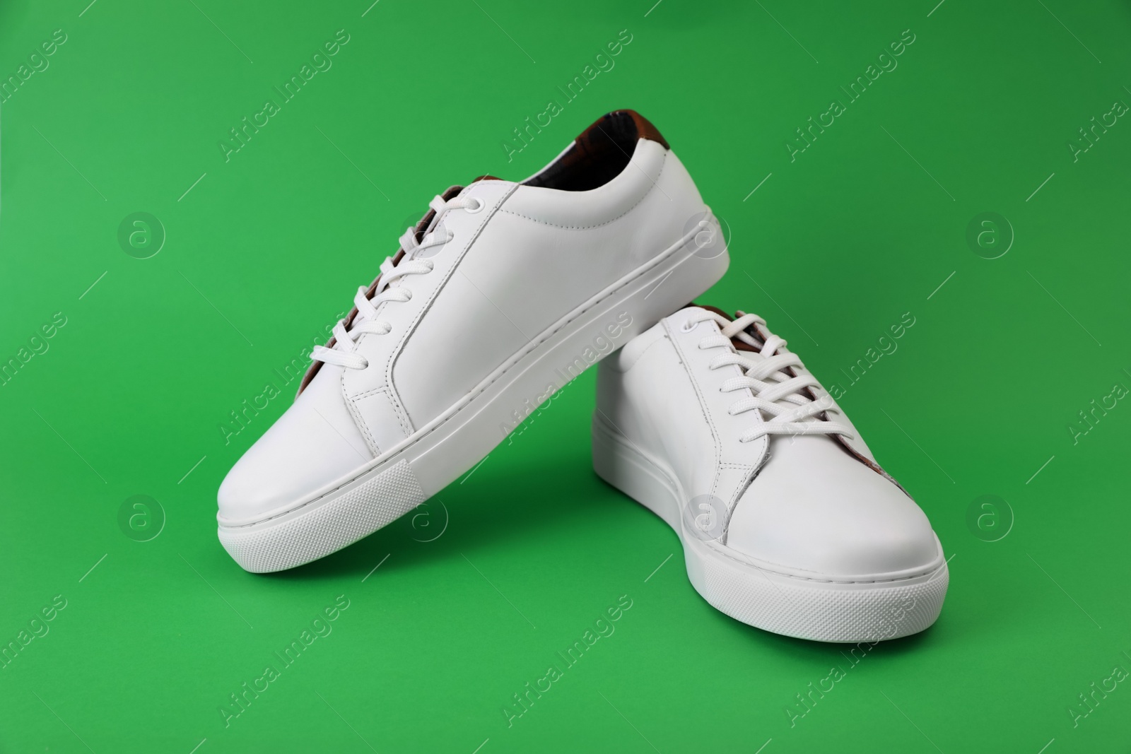 Photo of Pair of stylish sports shoes on green background