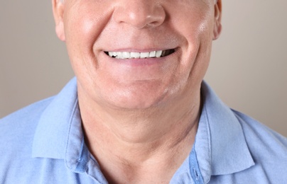 Mature man with healthy teeth on color background, closeup