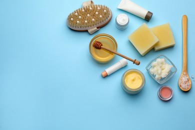 Photo of Flat lay composition with beeswax and cosmetic products on light blue background. Space for text