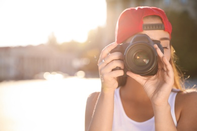 Photo of Young photographer taking picture with professional camera outdoors. Space for text