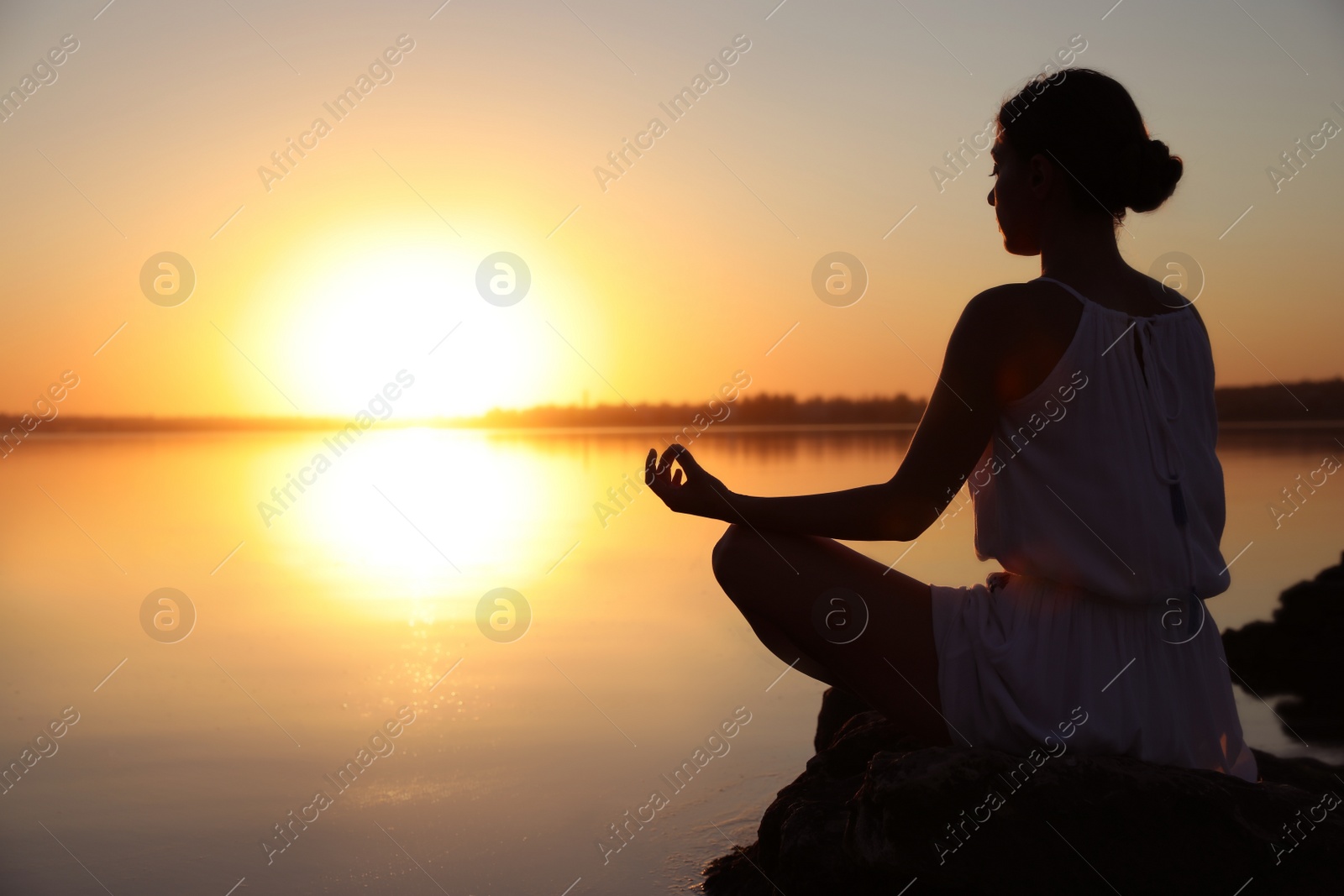 Photo of Woman practicing yoga near river on sunset. Healing concept