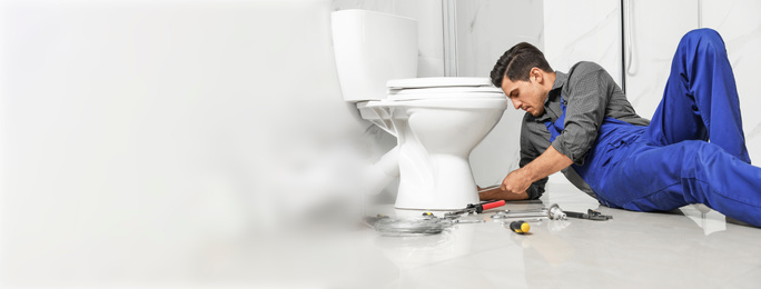 Professional plumber working with toilet bowl in bathroom, space for text. Banner design