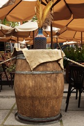 Photo of Traditional wooden barrel and vase with decorative plants in outdoor cafe