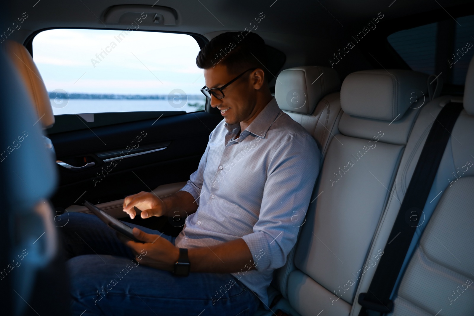 Photo of Handsome man using tablet on backseat of modern car