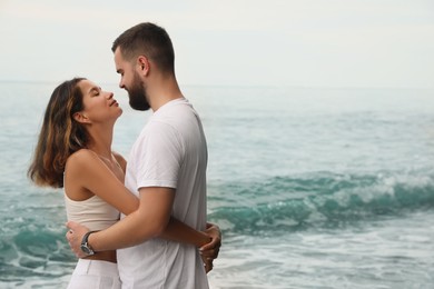 Photo of Happy young couple spending time together near sea. Space for text