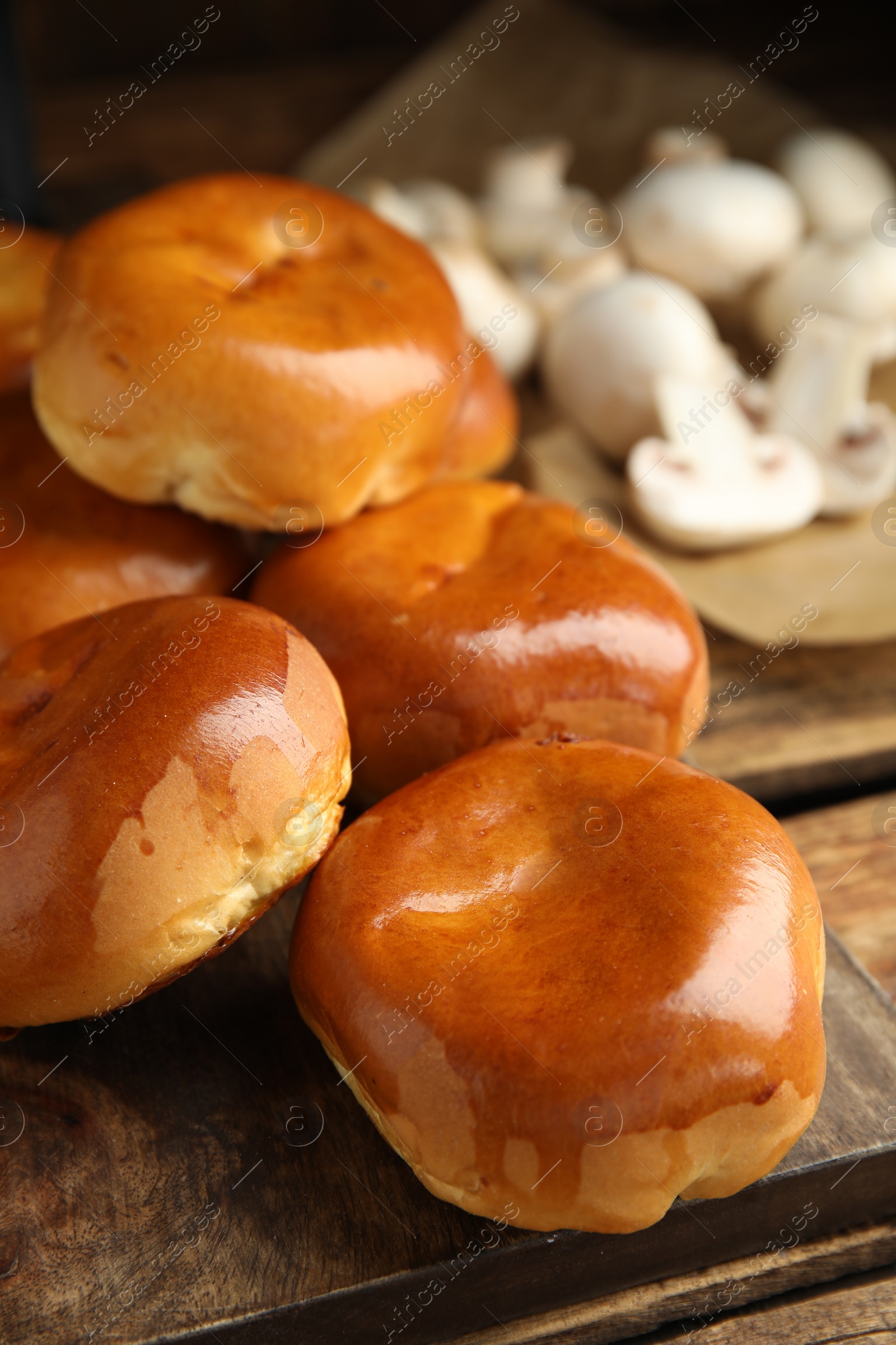 Photo of Delicious baked mushrooms pirozhki on wooden board