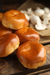 Photo of Delicious baked mushrooms pirozhki on wooden board