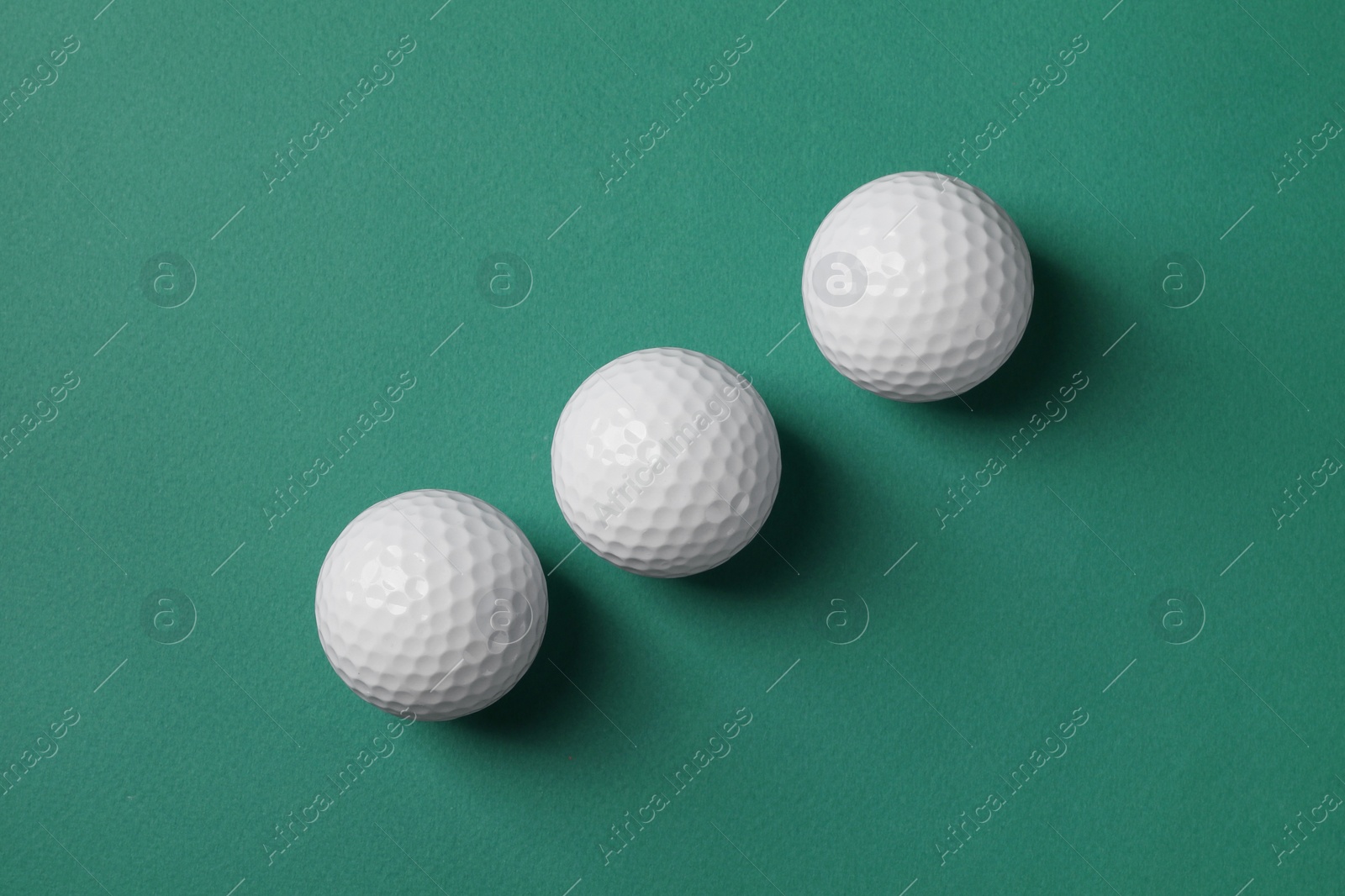 Photo of Three golf balls on green background, flat lay