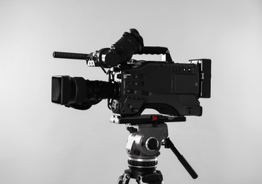 Modern professional video camera on light background