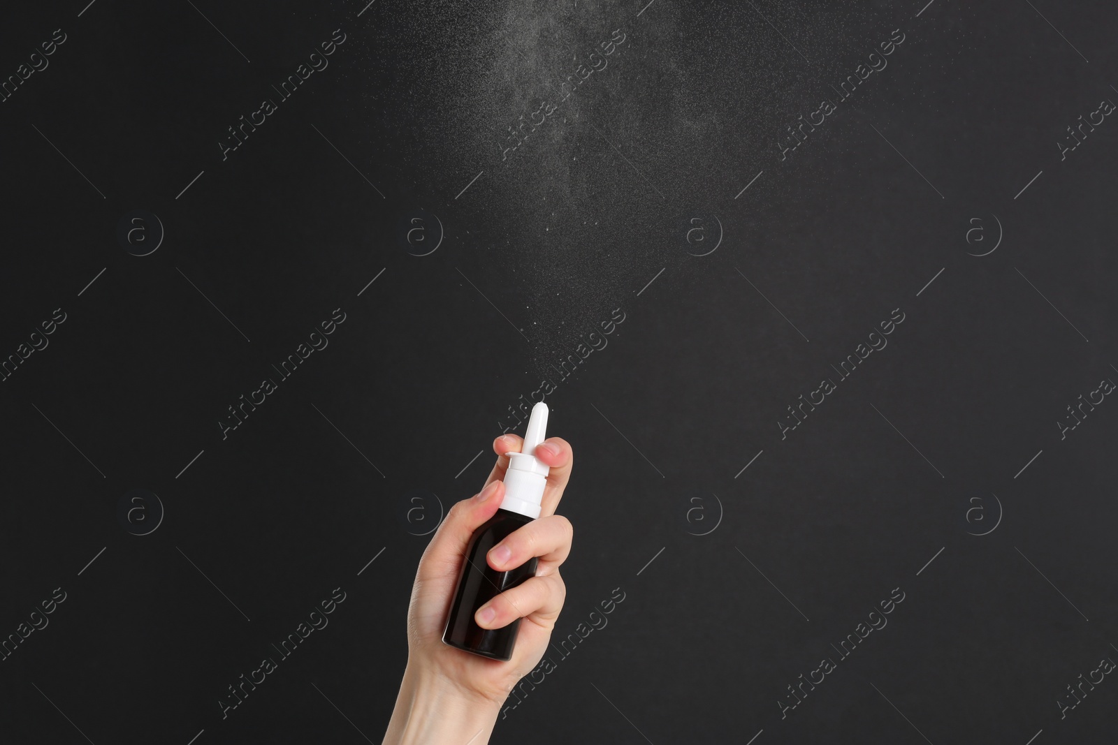 Photo of Woman spraying nasal medicine on black background, closeup. Space for text