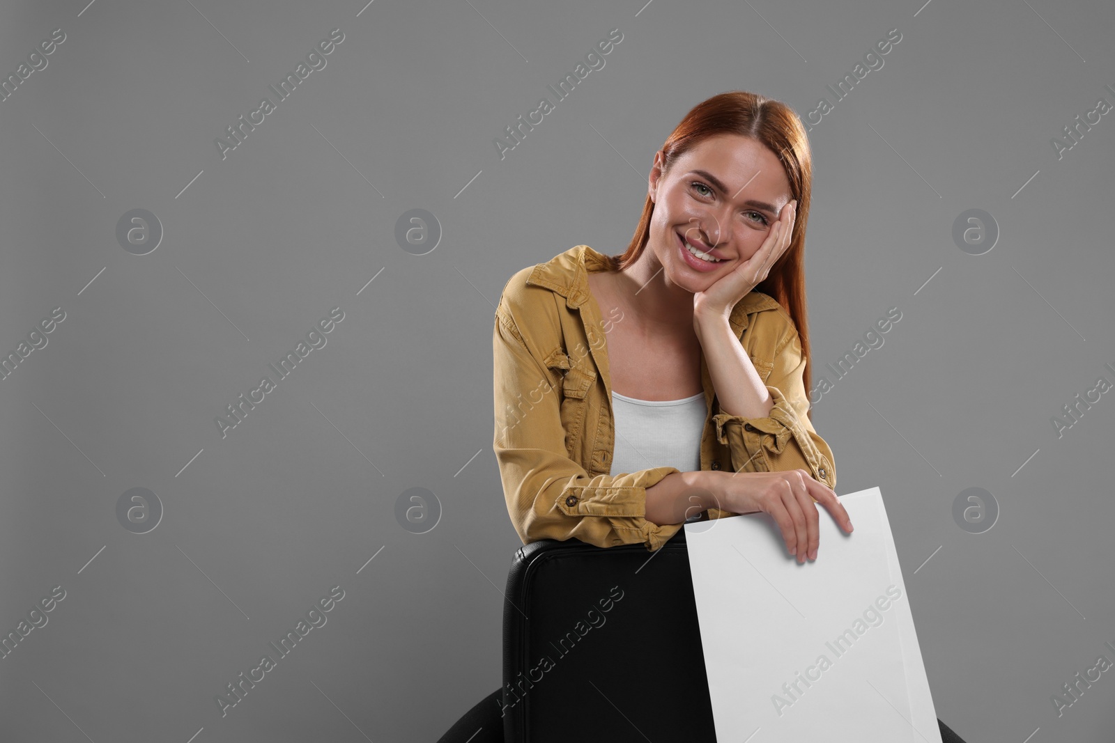 Photo of Casting call. Young woman with script on chair against grey background, space for text