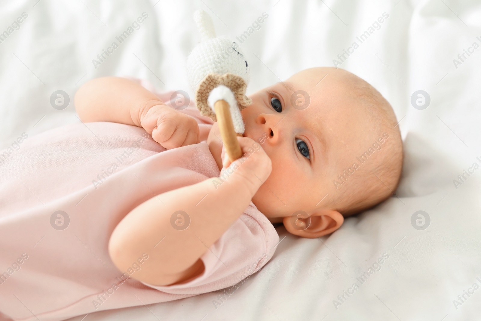 Photo of Cute little baby with toy on white sheets