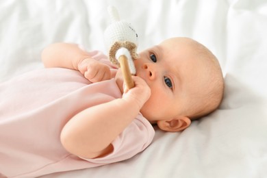 Photo of Cute little baby with toy on white sheets