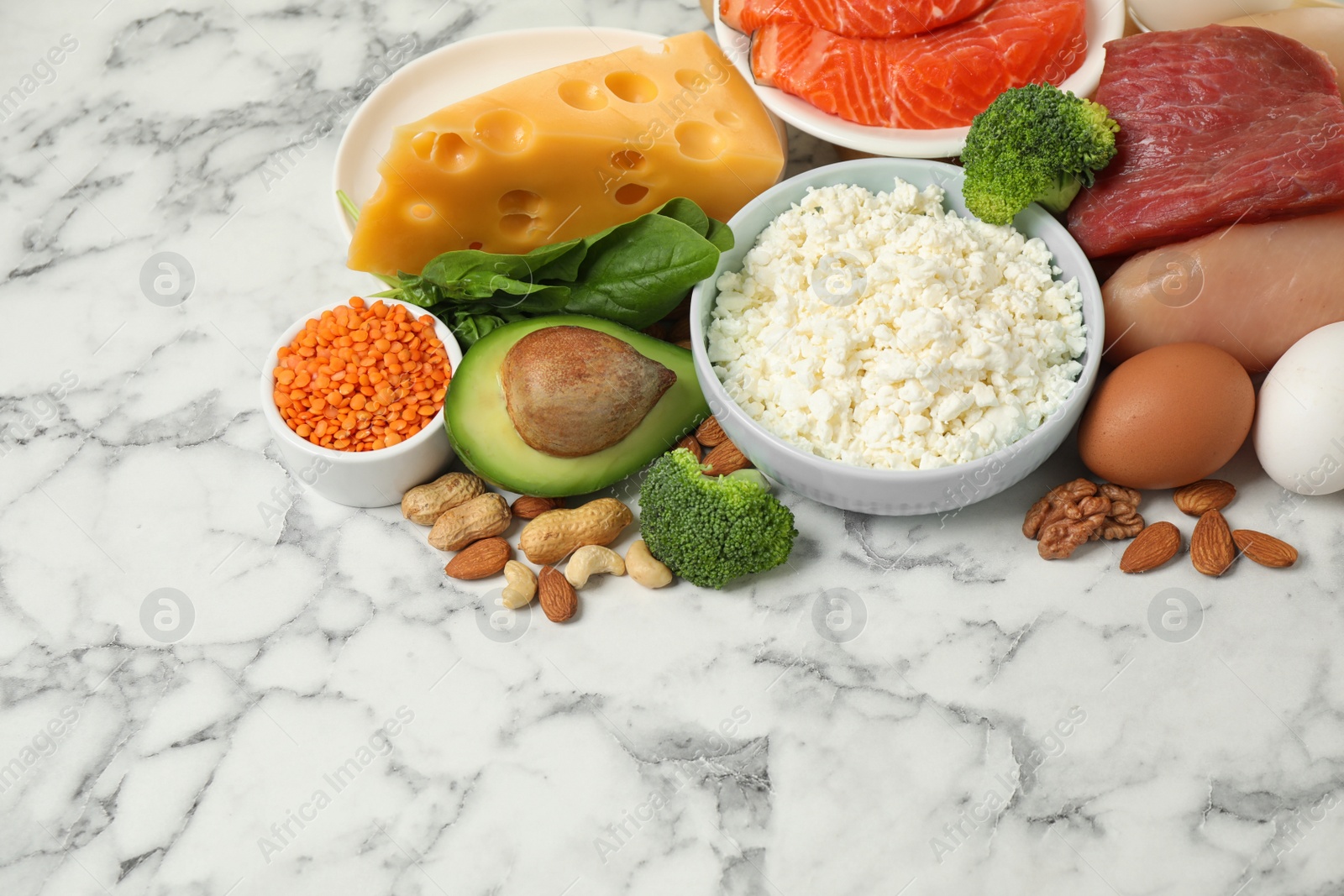 Photo of Different products rich in protein on white marble table