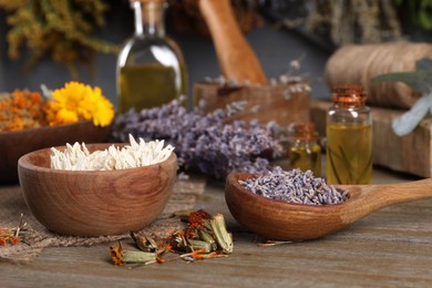 Photo of Bowl, spoon and many different dry herbs on wooden table