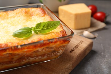 Photo of Tasty cooked lasagna in baking dish on grey table, closeup